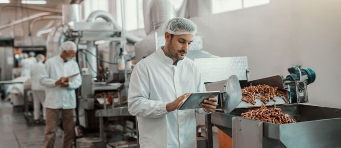 supervisor evaluating quality of food in food plant while holding tablet