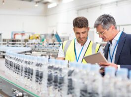 Supervisor and manager watching plastic bottles on conveyor belt