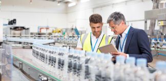 Supervisor and manager watching plastic bottles on conveyor belt