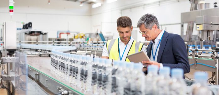 Supervisor and manager watching plastic bottles on conveyor belt